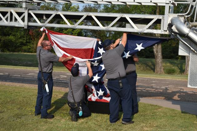 Sulphur Springs firefighters carefully take down the United State flag hanging from the ladder of one of their trucks.