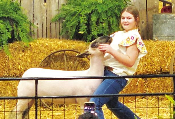 Ramsey Ragan, a Hopkins County 4-H member, poses her Reserve Champion lamb during the NETLA Sale of Champions, held at the end of the NETLA Junior Market Livestock Show last Saturday at the Hopkins County Regional Civic Center.